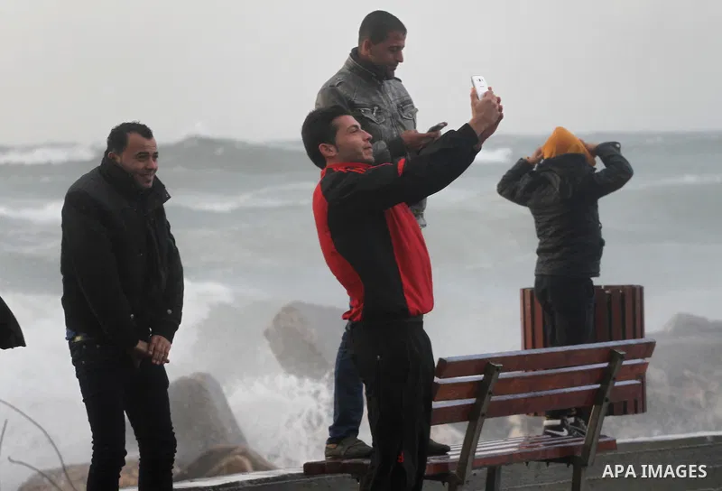 Palestinians stand in front of beach of Gaza city as waves crash fishermen's harbor during a rainy day on the first day of the new year on Jan. 01, 2016. Photo by Mohammed Asad