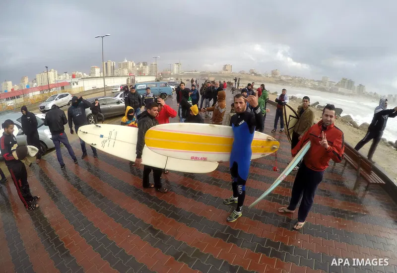 Palestinian youths prepare to surfing at beach of Gaza city as waves crash fishermen's harbor during a rainy day on the first day of the new year on Jan. 01, 2016. Photo by Mohammed Asad