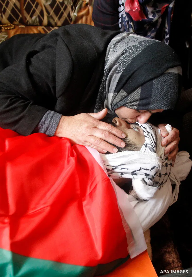 The mother of Palestinian Fadel Qawasma, mourns as she looks at his body during his funeral in the West Bank city of Hebron, on January 2, 2016. Photo by Wisam Hashlamoun