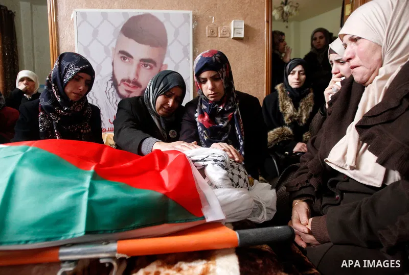 The mother of Palestinian Fadel Qawasma, mourns as she looks at his body during his funeral in the West Bank city of Hebron, on January 2, 2016. Photo by Wisam Hashlamoun