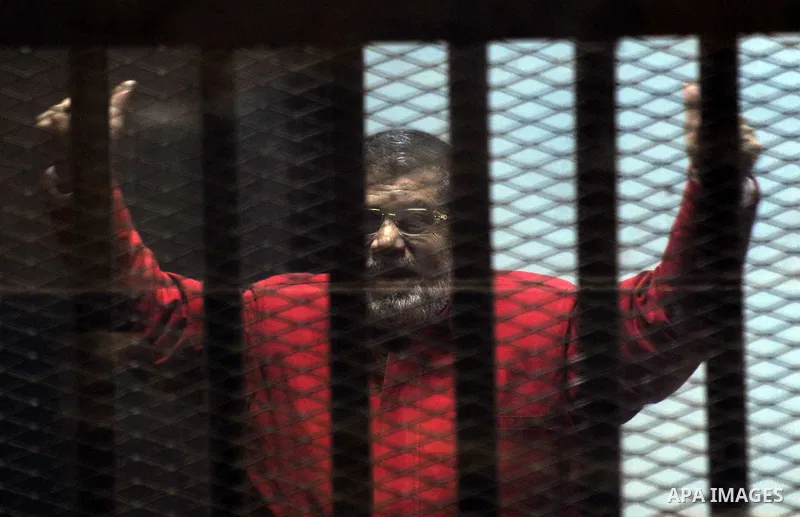 Ousted Egyptian president Mohammed Morsi gestures as he sits behind bars during his trail as part of the so-called 'Qatar espionage' case, in a court in Cairo on january 2, 2015. The defendants are accused of 'leaking im...
