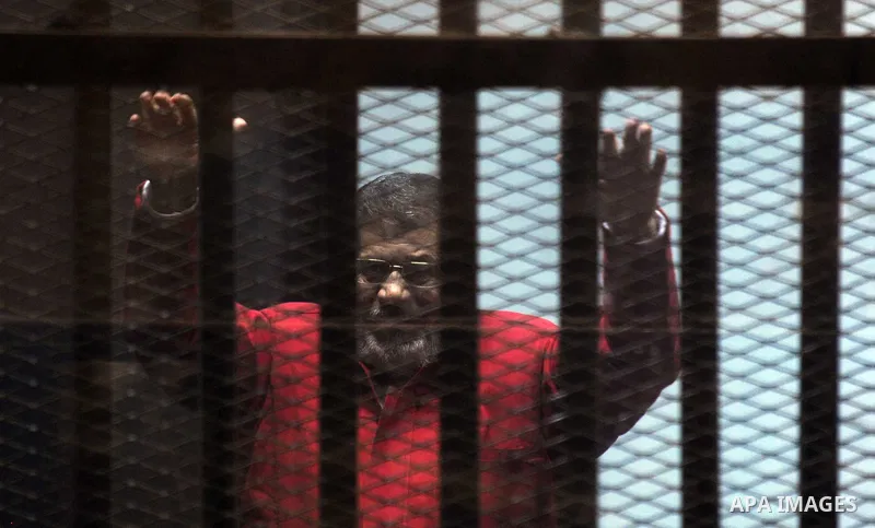 Ousted Egyptian president Mohammed Morsi gestures as he sits behind bars during his trail as part of the so-called 'Qatar espionage' case, in a court in Cairo on january 2, 2015. The defendants are accused of 'leaking im...