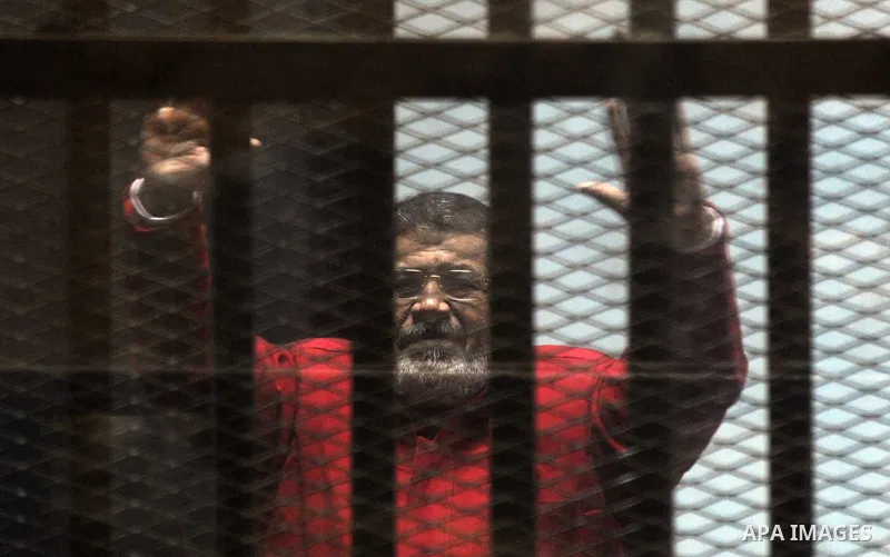 Ousted Egyptian president Mohammed Morsi gestures as he sits behind bars during his trail as part of the so-called 'Qatar espionage' case, in a court in Cairo on january 2, 2015. The defendants are accused of 'leaking im...