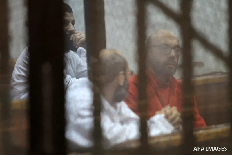 Defendants of Egyptian Muslim Brotherhood sit behind bars during the 'Qatar espionage' case, along with ousted Islamist president Mohamed Morsi (unseen) in a court in Cairo on Jan. 04, 2015. The defendants are accused of...