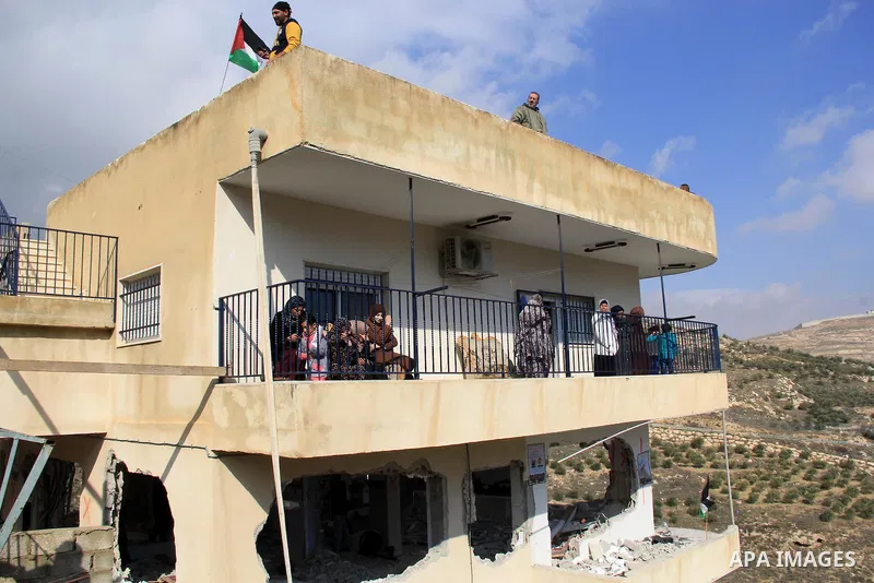 Palestinian women sit on the balcony above the destroyed home of Bahaa Allyan, a fellow Palestinian who killed three Israelis in a shooting and stabbing attack with an accomplice on a bus in October, after Israeli forces...