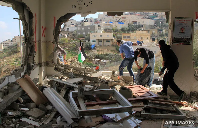 Palestinian men inspect the damaged interior of the home of Bahaa Allyan, a Palestinian who killed three Israelis in a shooting and stabbing attack with an accomplice on a bus in October, after Israeli forces used jackha...