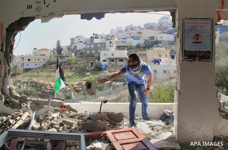 Palestinian men inspect the damaged interior of the home of Bahaa Allyan, a Palestinian who killed three Israelis in a shooting and stabbing attack with an accomplice on a bus in October, after Israeli forces used jackha...