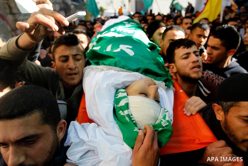 Mourners carry the body of Palestinian Ahmad Kawazbeh, 17, whom the Israeli military said was shot and killed by Israeli security forces on Tuesday after he stabbed an Israeli soldier, during his funeral in the West Bank...