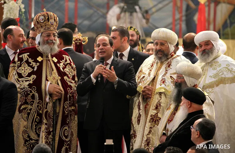 Egyptian President Abdel Fattah el-Sisi waves to the worshipers during his visit to the St. Mark's Coptic Orthodox Cathedral on the eve of the orthodox Christmas mass led by Egyptian Coptic Pope Tawadros II in Cairo on J...