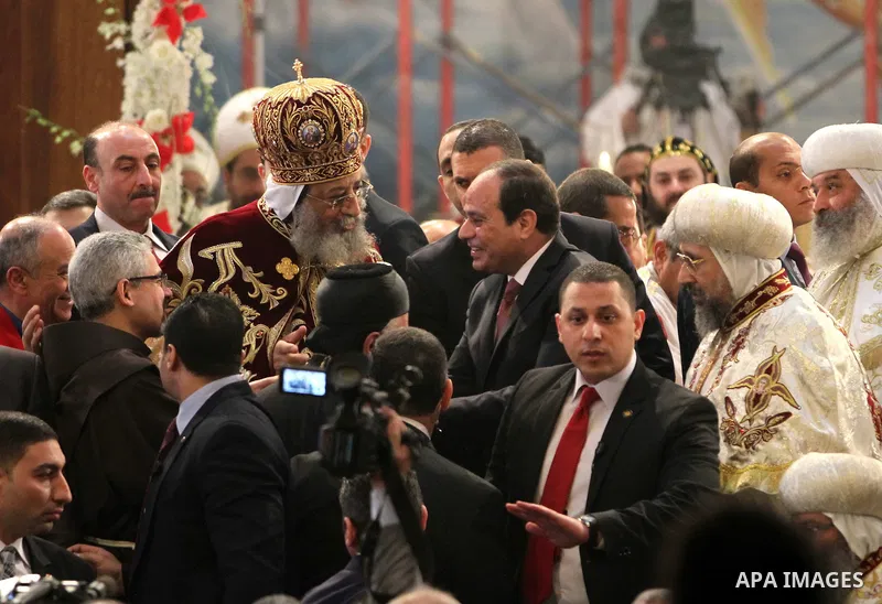 Egyptian President Abdel Fattah el-Sisi waves to the worshipers during his visit to the St. Mark's Coptic Orthodox Cathedral on the eve of the orthodox Christmas mass led by Egyptian Coptic Pope Tawadros II in Cairo on J...