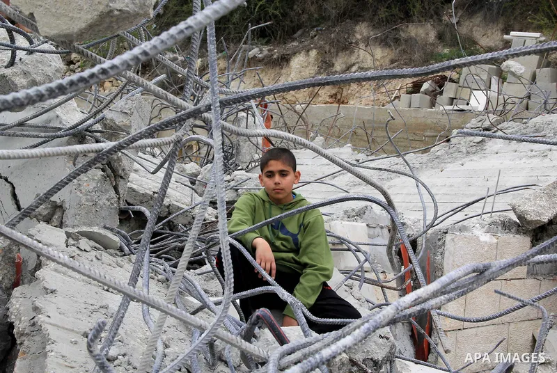 A Palestinian boy stands on the rubble of his family house that was demolished by Jerusalem municipality workers in Jerusalem on Jan. 07, 2016. Israeli police Thursday demolished two Palestinian-owned homes in Ein el-Law...