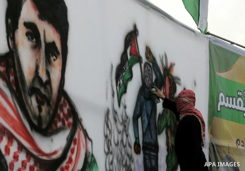 A Palestinian paints a mural during a rally in Khan Yunis in the southern Gaza Strip on January 7, 2016. The rally was held to honor the families of dead militants from the armed wing, who Hamas said participated in impr...
