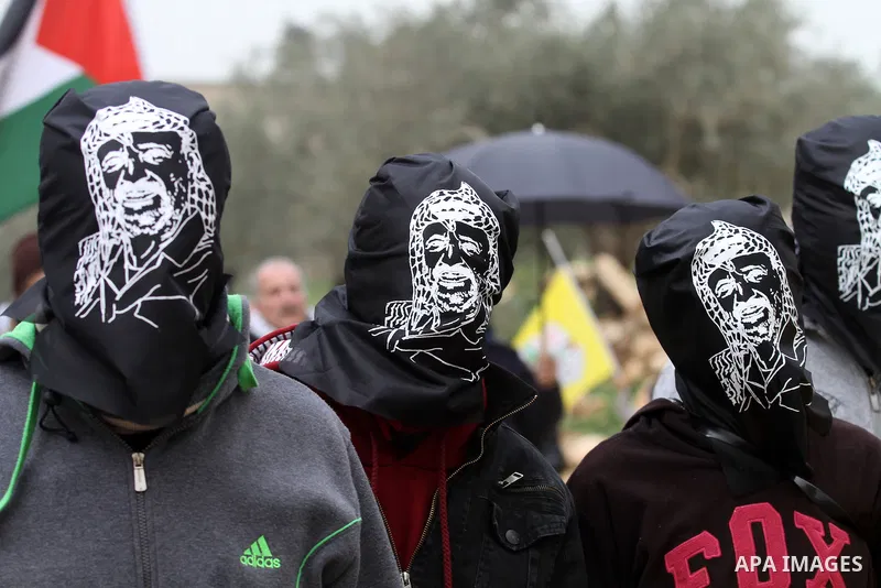 Masked Palestinian protesters look on during clashes with Israeli security forces following a protest against the expropriation of Palestinian land by Israel in the West Bank village of Kafr Qaddum, near the northern cit...