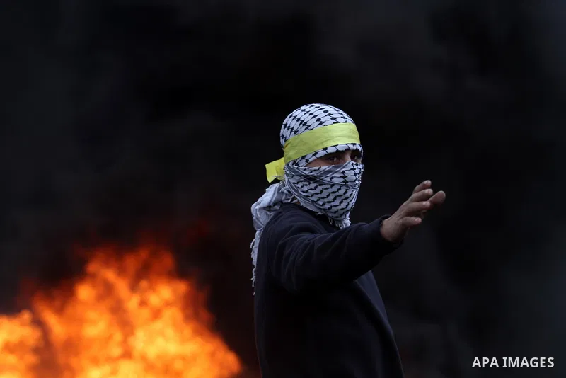 A Masked Palestinian protester looks on during clashes with Israeli security forces following a protest against the expropriation of Palestinian land by Israel in the West Bank village of Kafr Qaddum, near the northern c...