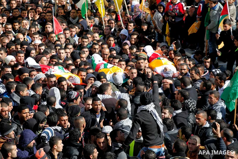 Mourners carry the bodies of four Palestinians, who were killed by Israeli security forces after they perpetrated attacks in the southern West Bank, during their funeral in the West Bank village of Sair on January 9, 201...