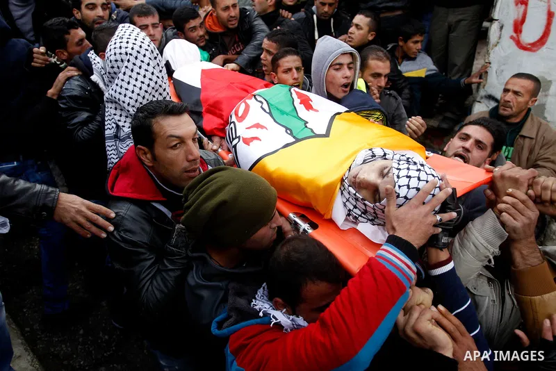 Mourners carry the bodies of four Palestinians, who were killed by Israeli security forces after they perpetrated attacks in the southern West Bank, during their funeral in the West Bank village of Sair on January 9, 201...