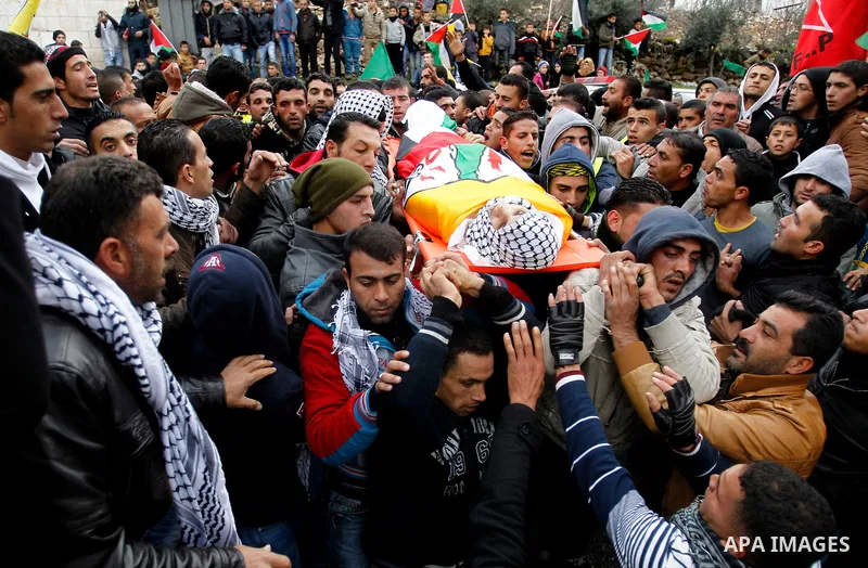 Mourners carry the bodies of four Palestinians, who were killed by Israeli security forces after they perpetrated attacks in the southern West Bank, during their funeral in the West Bank village of Sair on January 9, 201...