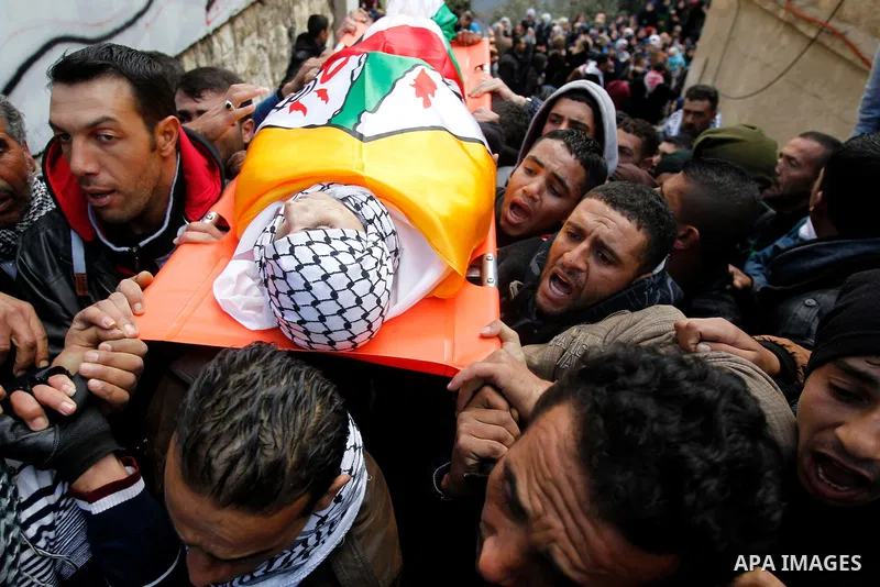 Mourners carry the bodies of four Palestinians, who were killed by Israeli security forces after they perpetrated attacks in the southern West Bank, during their funeral in the West Bank village of Sair on January 9, 201...