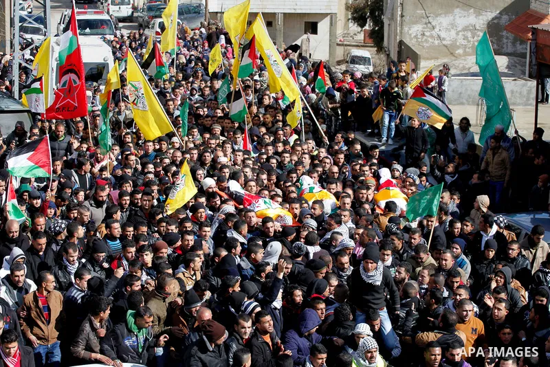 Mourners carry the bodies of four Palestinians, who were killed by Israeli security forces after they perpetrated attacks in the southern West Bank, during their funeral in the West Bank village of Sair on January 9, 201...