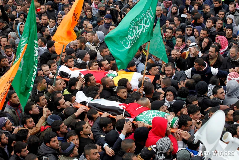 Mourners carry the bodies of four Palestinians, who were killed by Israeli security forces after they perpetrated attacks in the southern West Bank, during their funeral in the West Bank village of Sair on January 9, 201...