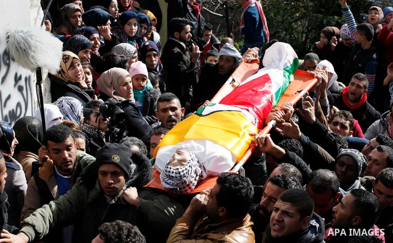 Mourners carry the bodies of four Palestinians, who were killed by Israeli security forces after they perpetrated attacks in the southern West Bank, during their funeral in the West Bank village of Sair on January 9, 201...