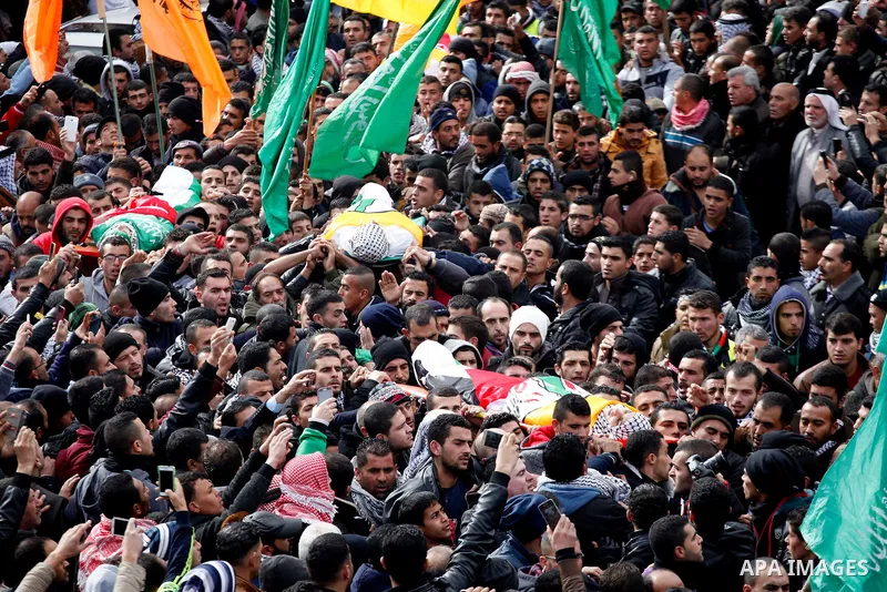 Mourners carry the bodies of four Palestinians, who were killed by Israeli security forces after they perpetrated attacks in the southern West Bank, during their funeral in the West Bank village of Sair on January 9, 201...