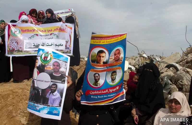 Relatives of four Palestinian men abducted by unidentified masked gunmen on August 19, hold their relatives' pictures during a protest demanding for their return, in front of the Gaza-Egypt border in Rafah in the souther...