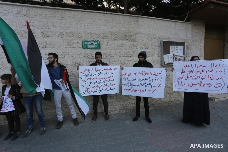 Palestinians hold banners during a protest to show solidarity with the Syrians of Madaya on hunger caused by the siege, in front of Red cross office, in Gaza city on January 12, 2016. Photo by Mohammed Asad