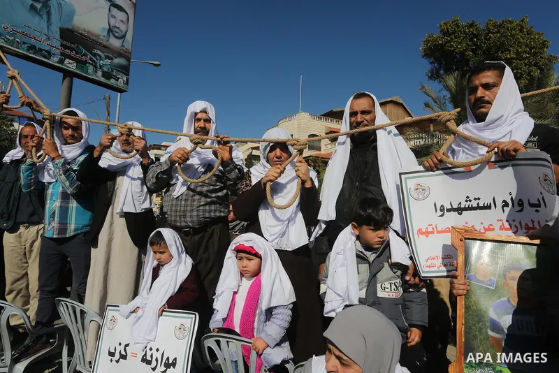 Palestinian families of martyrs, hold banners during a protest to demand their salaries, in front of the headquarters of the Council of Ministers, in Gaza City on January 12, 2016. Photo by Mohammed Asad