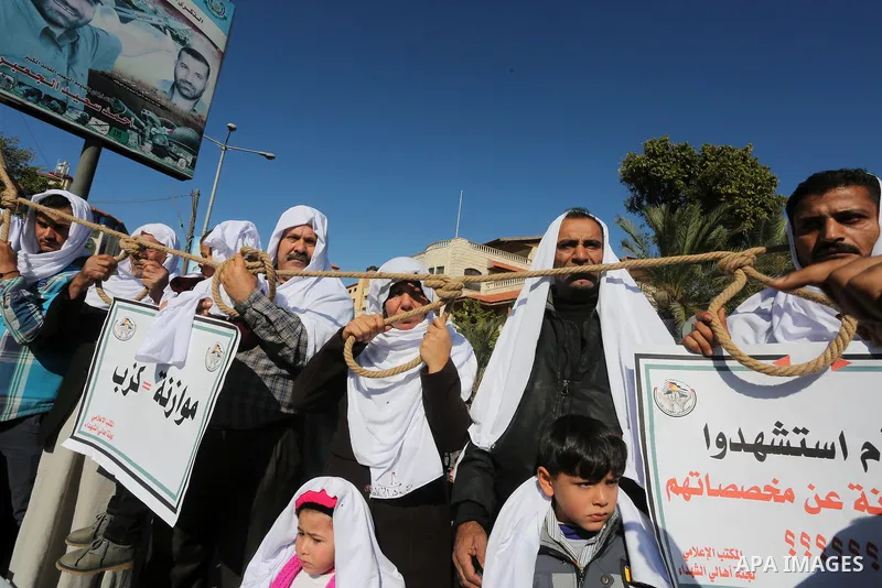Palestinian families of martyrs, hold banners during a protest to demand their salaries, in front of the headquarters of the Council of Ministers, in Gaza City on January 12, 2016. Photo by Mohammed Asad