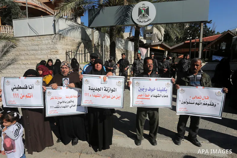 Palestinian families of martyrs, hold banners during a protest to demand their salaries, in front of the headquarters of the Council of Ministers, in Gaza City on January 12, 2016. Photo by Mohammed Asad