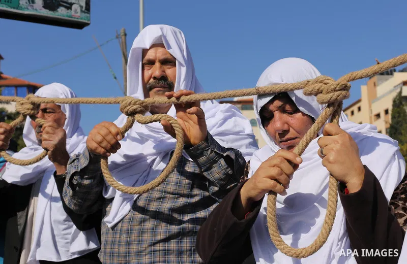 Palestinian families of martyrs, hold banners during a protest to demand their salaries, in front of the headquarters of the Council of Ministers, in Gaza City on January 12, 2016. Photo by Mohammed Asad