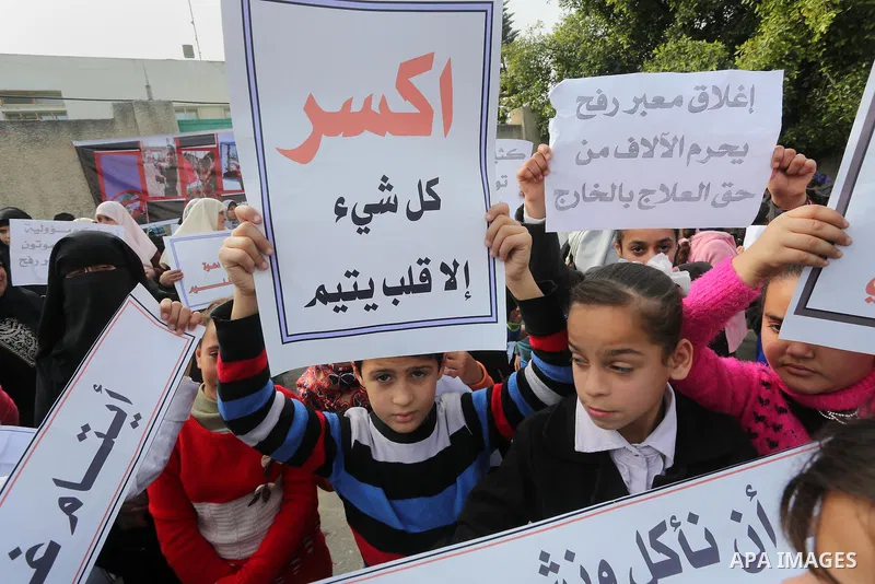 Palestinians hold banners during a protest demanding the Egyptian authorities for the opening of the Rafah crossing in front of the Egyptian embassy, in Gaza city, on January 14, 2016. Photo by Mohammed Asad