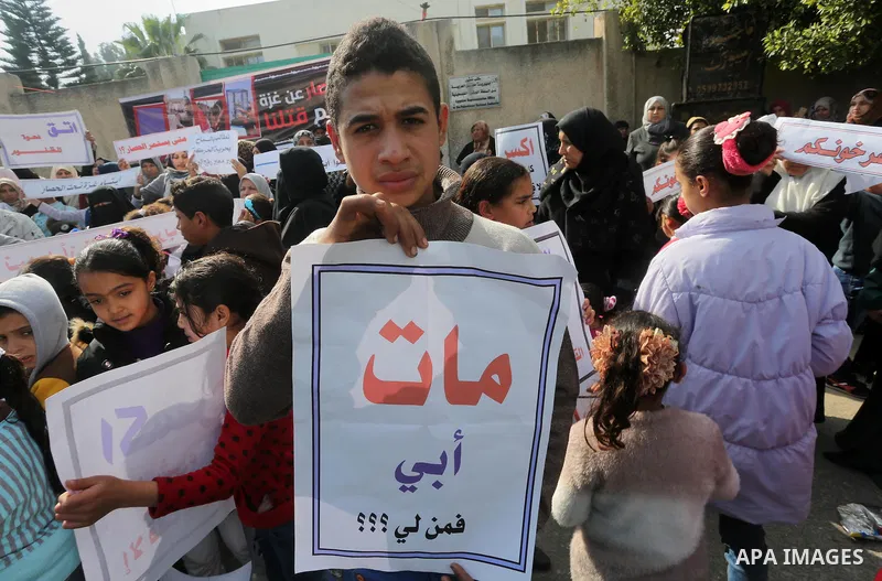 Palestinians hold banners during a protest demanding the Egyptian authorities for the opening of the Rafah crossing in front of the Egyptian embassy, in Gaza city, on January 14, 2016. Photo by Mohammed Asad