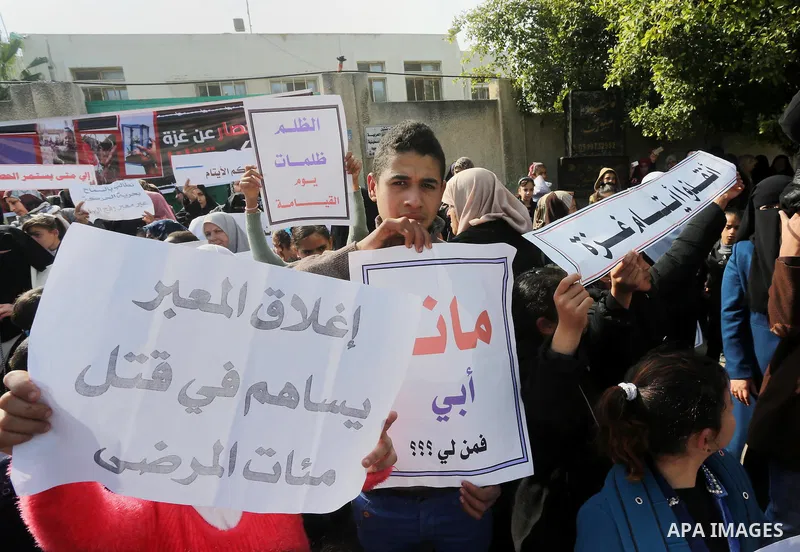 Palestinians hold banners during a protest demanding the Egyptian authorities for the opening of the Rafah crossing in front of the Egyptian embassy, in Gaza city, on January 14, 2016. Photo by Mohammed Asad