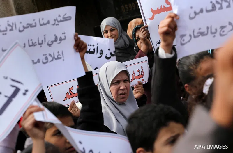 Palestinians hold banners during a protest demanding the Egyptian authorities for the opening of the Rafah crossing in front of the Egyptian embassy, in Gaza city, on January 14, 2016. Photo by Mohammed Asad
