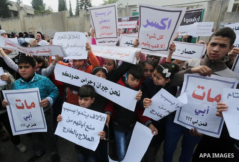 Palestinians hold banners during a protest demanding the Egyptian authorities for the opening of the Rafah crossing in front of the Egyptian embassy, in Gaza city, on January 14, 2016. Photo by Mohammed Asad