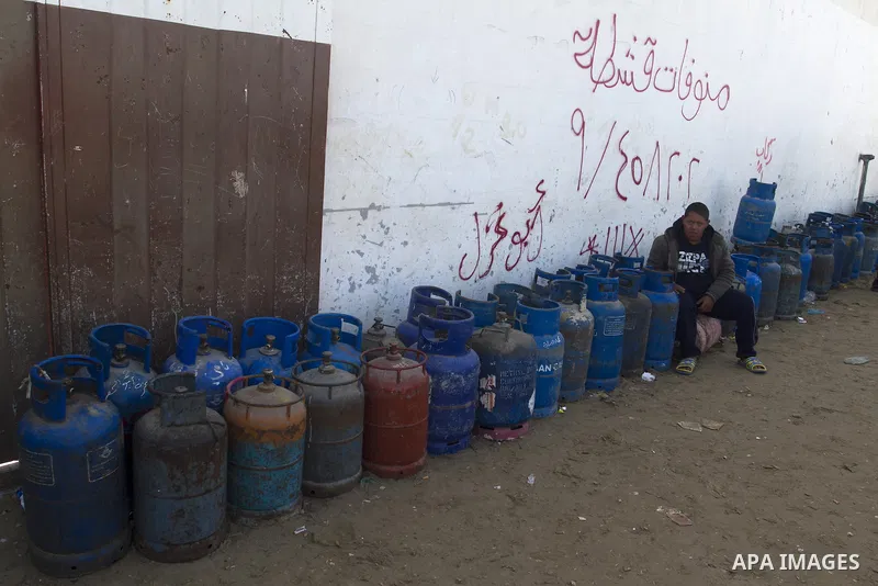 Palestinians wait to fill a cooking gas canister at a station in Rafah in southern Gaza Strip on January 14, 2016. Gas used for heating and cooking in Gaza is in short supply because of rationing. The power shortage stem...