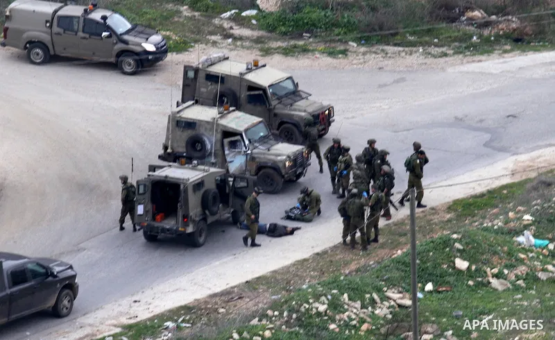 Israeli security forces gather around the body of a Palestinian man who was shot dead following a reported stabbing attack in the village of Assira al-Shamaliya near Nablus, in the occupied West Bank, on January 14, 2016...