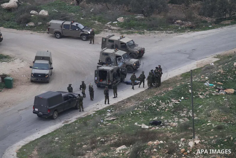 Israeli security forces gather around the body of a Palestinian man who was shot dead following a reported stabbing attack in the village of Assira al-Shamaliya near Nablus, in the occupied West Bank, on January 14, 2016...