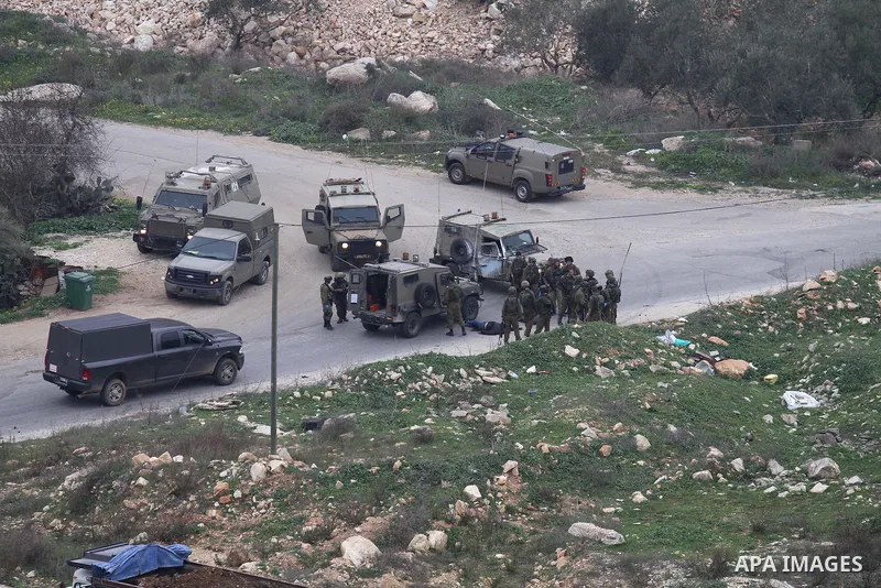 Israeli security forces gather around the body of a Palestinian man who was shot dead following a reported stabbing attack in the village of Assira al-Shamaliya near Nablus, in the occupied West Bank, on January 14, 2016...