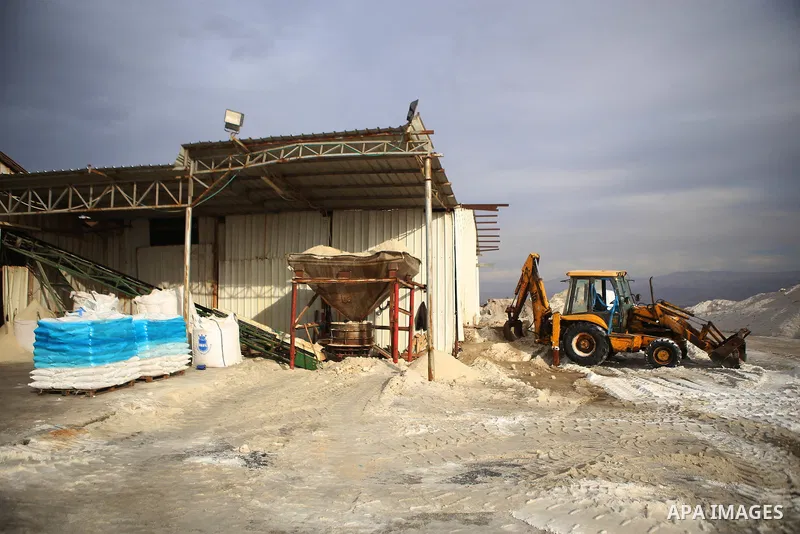 A Palestinian worker uses a bulldozer to load the salt extraction "raw material" from the Dead Sea, in the West Bank city of Jericho on January 14, 2016. The Dead Sea also called the Salt Sea, is a salt lake with borders...