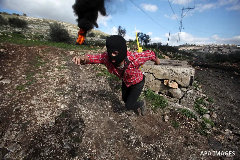 A Palestinian protester runs to take a cover during clashes Israeli security forces following a protest against the expropriation of Palestinian land by Israel in the West Bank village of Kafr Qaddum, near the northern c...