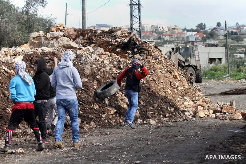 Palestinian protesters hurl stones toward Israeli security forces during clashes following a protest against the expropriation of Palestinian land by Israel in the West Bank village of Kafr Qaddum, near the northern city...