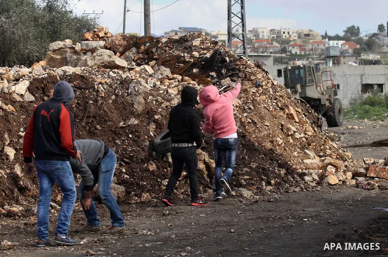 Palestinian protesters hurl stones toward Israeli security forces during clashes following a protest against the expropriation of Palestinian land by Israel in the West Bank village of Kafr Qaddum, near the northern city...