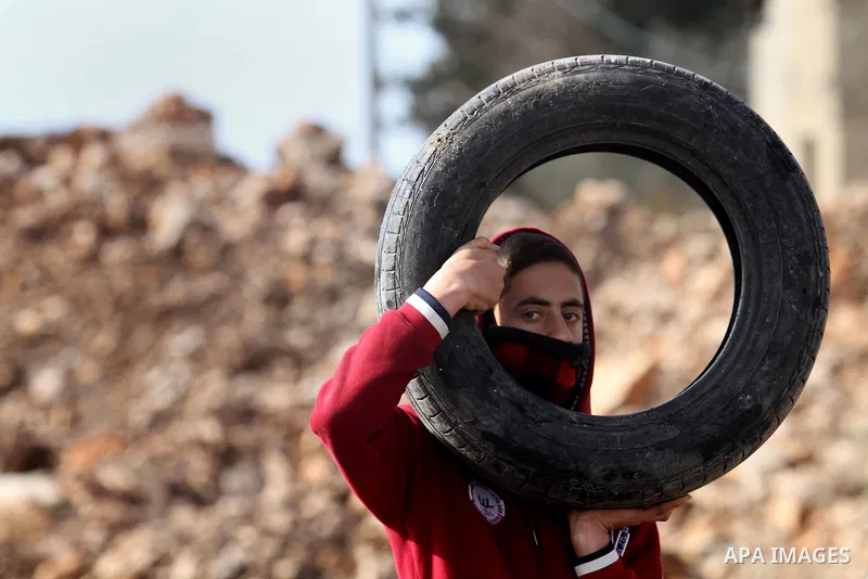 A Palestinian protester carry tires during clashes with Israeli secrity forces following a protest against the expropriation of Palestinian land by Israel in the West Bank village of Kafr Qaddum, near the northern city o...
