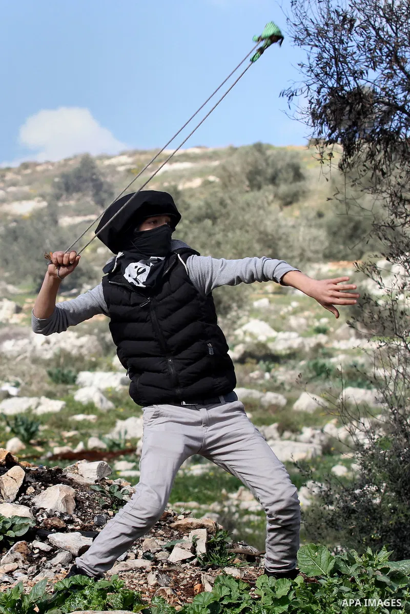 A Palestinian protester uses a slingshot to hurl stones toward Israeli security forces during clashes following a protest against the expropriation of Palestinian land by Israel in the West Bank village of Kafr Qaddum, n...