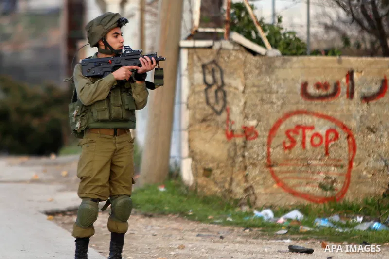 A member of Israeli security forces aims his weapon at Palestinian protesters during clashes in Jalazoun refugee camp near the West Bank city of Ramallah on Jan. 15, 2016. Photo by Shadi Hatem