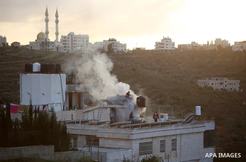 Palestinians try to take control of the fire on roof of house after Israeli security forces fired tear gas canister during clashes in Jalazoun refugee camp near the West bank city of Ramallah on Jan. 15, 2016. Photo by S...