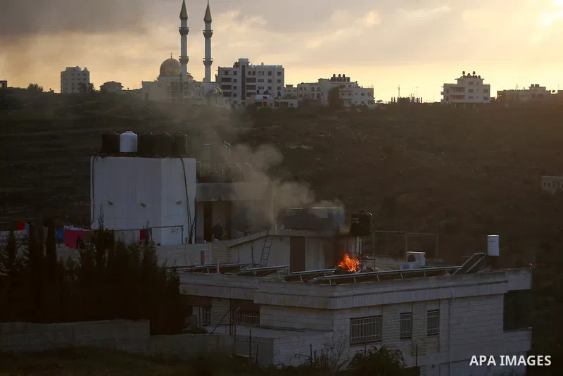 Palestinians try to take control of the fire on roof of house after Israeli security forces fired tear gas canister during clashes in Jalazoun refugee camp near the West bank city of Ramallah on Jan. 15, 2016. Photo by S...